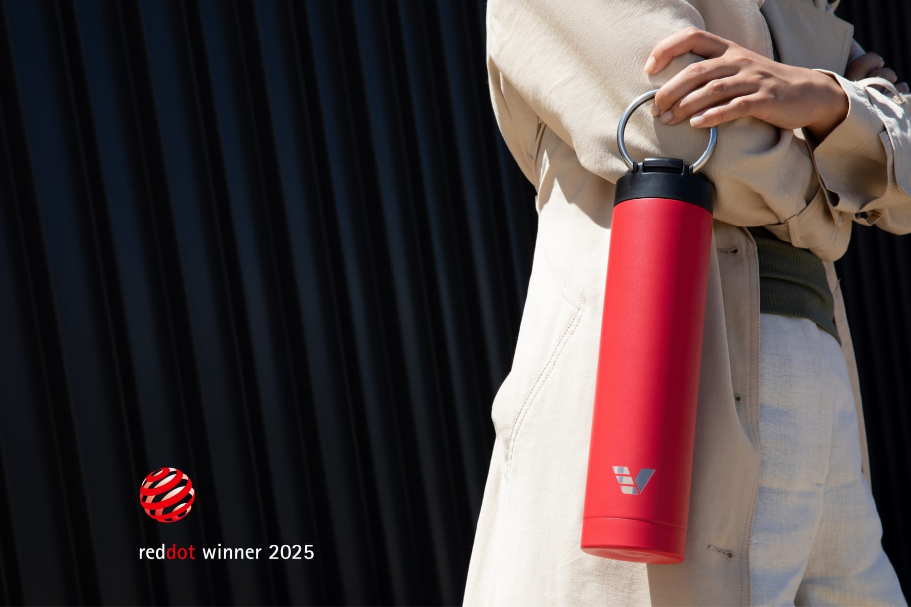 A female holding her Ever Vessel Super Maxi Red water bottle by the integrated handle  with the Red Dot Design Award logo.