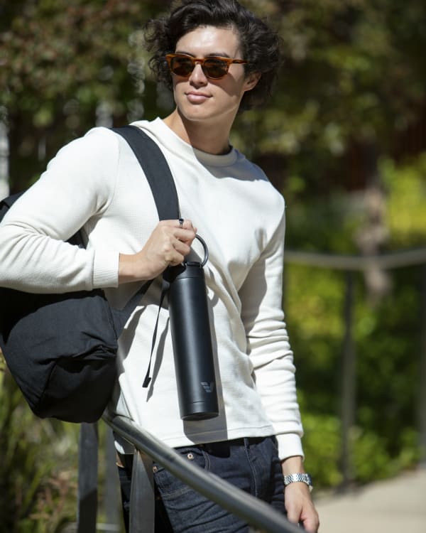 Man with an Ever Vessel Super Maxi Black Sand stainless steel water bottle held by the integrated carry handle.