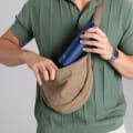 A male putting her Ever Vessel Mini Blue small water bottle into a small sling.