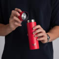 A male holding his Ever Vessel Mini Red small water bottle with the lid off.