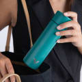 A female putting an Ever Vessel Mini Teal small water bottle into laptop bag.