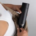 A female putting an Ever Vessel Mini Black Sand small water bottle into a small sling.