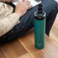 An Ever Vessel Super Maxi Teal  green stainless steel water bottle with flip top lid open next to a male on his laptop.