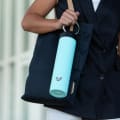 A female carrying her Ever Vessel Super Maxi Mint Green stainless steel water bottle by the integrated carry handle from work.