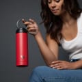 A female holding her Ever Vessel Maxi Red stainless steel water bottle by the integrated carry handle.