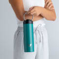A female holding her Ever Vessel Maxi Teal green stainless steel water bottle by the integrated carry handle.