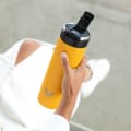 A female about to drink from her Ever Vessel Maxi Yellow stainless steel water bottle with the flip top lid open.