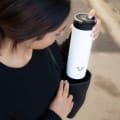 A female putting her Ever Vessel Maxi White stainless steel water bottle into her work bag.