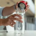 A male taking off the red lid from his Ever Vessel Glass water bottle at his work desk.