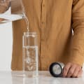 A male filling his Ever Vessel Glass water bottle with stainless steel lid at the kitchen bench.