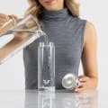 A female filling her Ever Vessel Glass water bottle with stainless steel lid at the kitchen bench.