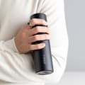 A male holding his Ever Vessel Mini Personalized Black small water bottle with the name Joshua engraved on side.