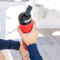A male about to drink from his Ever Vessel Super Maxi Red stainless steel water bottle with leak-proof flip lid open on a yacht.