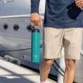 A male holding his Ever Vessel Super Maxi Teal Green stainless steel water bottle by the integrated carry handle at the marina dock.