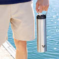 A male holding his Ever Vessel Super Maxi stainless steel water bottle by the integrated carry handle at the marina dock.