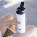 A female holding her Ever Vessel Maxi White Sand stainless steel water bottle with leak-proof flip top lid on a yacht.