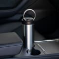 An Ever Vessel Maxi stainless steel water bottle sitting in car cup holder with integrated carry handle deployed.