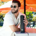A male grabbing his Ever Vessel Super Maxi Black stainless steel water bottle from an outside table at an event.