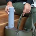 A female putting her Ever Vessel Mini Lilac small water bottle fitting into her handbag.