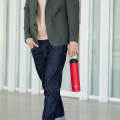 A male carrying his Ever Vessel Super Maxi Red stainless steel water bottle by the carry handle on the way to work.