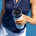 A female about to drink from her Ever Vessel Maxi White stainless steel water bottle with leak-proof flip top open on the tennis court.