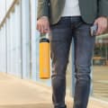 Male carrying his Super Maxi Yellow stainless steel water bottle by the integrated handle on the way to the office.