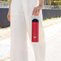 Female carrying her Ever Vessel Maxi Red stainless steel water bottle by the integrated carry handle trackside.