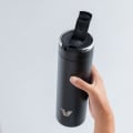 A female holding an Ever Vessel Maxi Black stainless steel water bottle with the leak-proof flip top open.