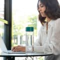 A female at a shared office desk with her Ever Vessel Glass water bottle with teal green lid by her side.