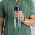 A male holding his Ever Vessel Glass water bottle with black lid.
