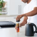 A male in the kitchen screwing on the lid of his Ever Vessel Glass Multi double walled glass tea infuser water bottle with a black lid and tea infusing inside.