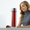 A female at her desk with her Ever Vessel Glass Multi tea infuser water bottle with tea inside by her side.
