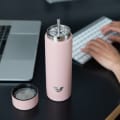An Ever Vessel Multi Rose pink stainless steel tea infuser water bottle with the Straw Attachment accessory sitting on a desk.