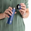 Male about to drink from an Ever Vessel Mini Blue small water bottle with the lid off.