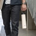 Male carrying his Super Maxi Luna White stainless steel water bottle by the integrated handle on the way to study.
