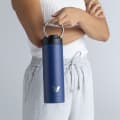 Female carrying her Ever Vessel Maxi Blue stainless steel water bottle by the integrated carry handle at home.