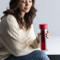 Female holding an Ever Vessel Glass Multi double walled glass tea infuser bottle with a red lid and berry tea inside.