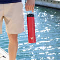 Ever Vessel Red Super Maxi insulated water bottle being held by handle on a jetty