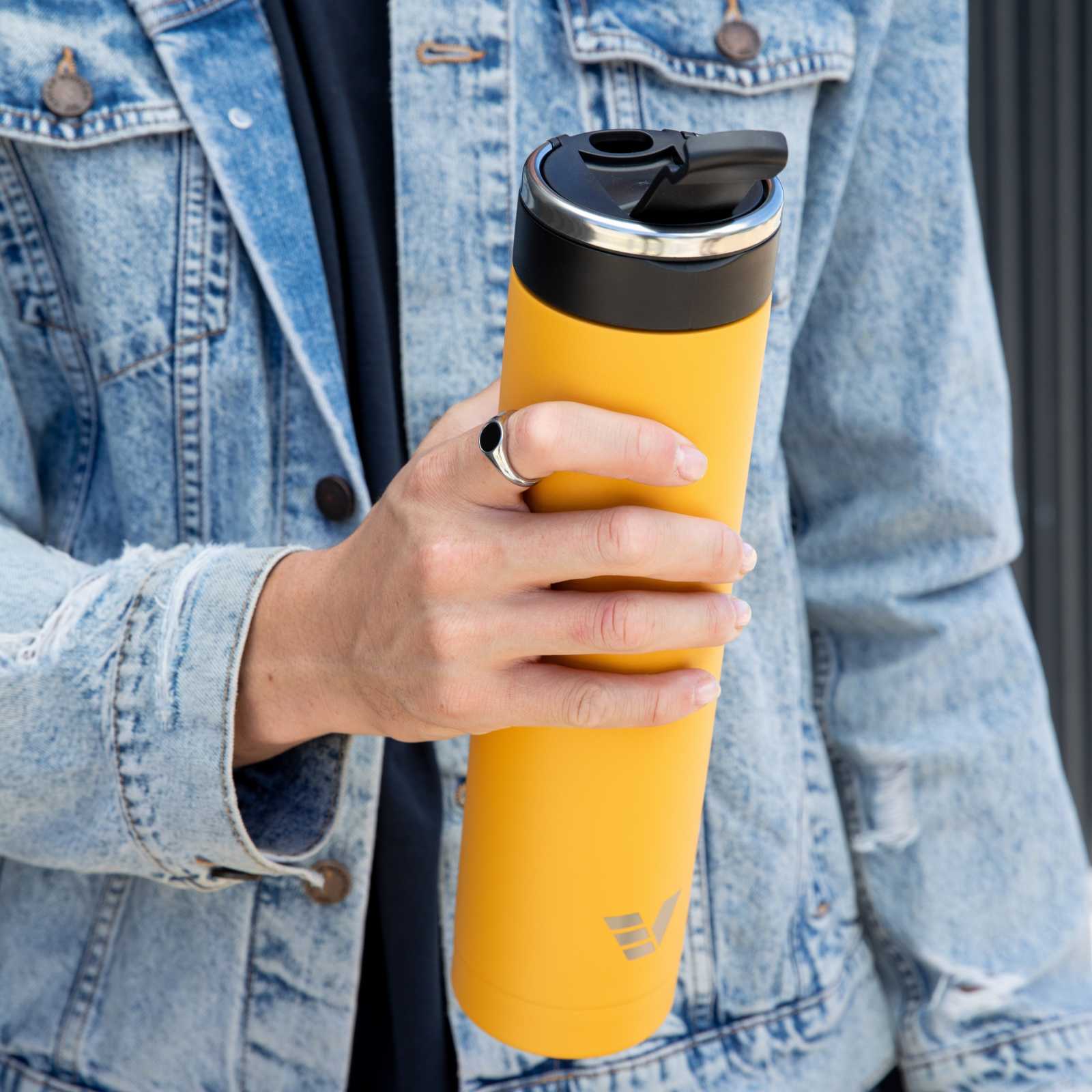 A male holding an Ever Vessel Super Maxi Yellow stainless steel water bottle with the flip top lid open.