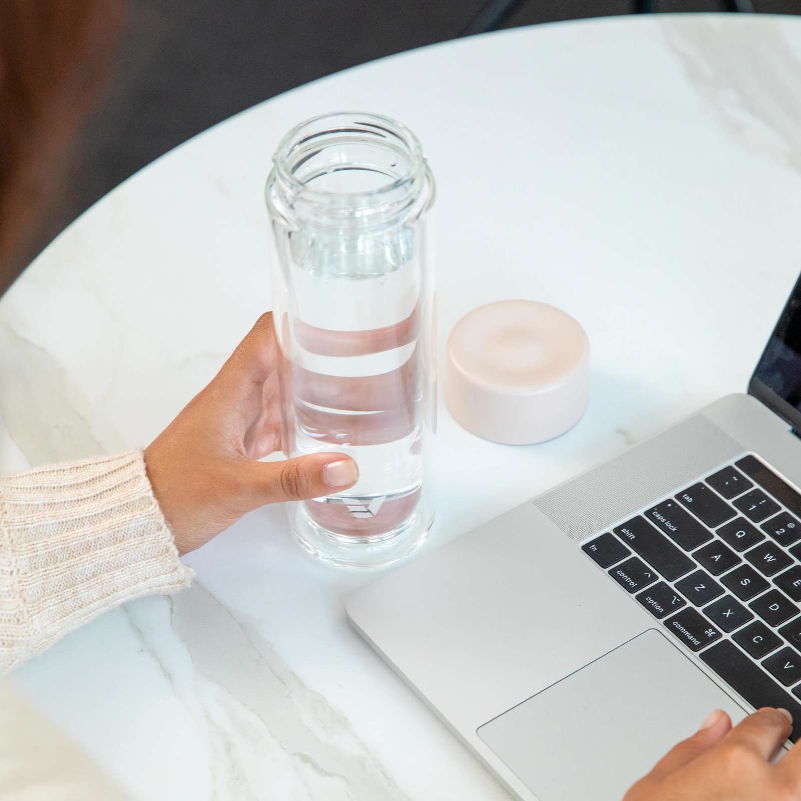A female about to drink from her Ever Vessel Glass Multi double walled glass tea infuser bottle with the desert beige lid removed at her desk.