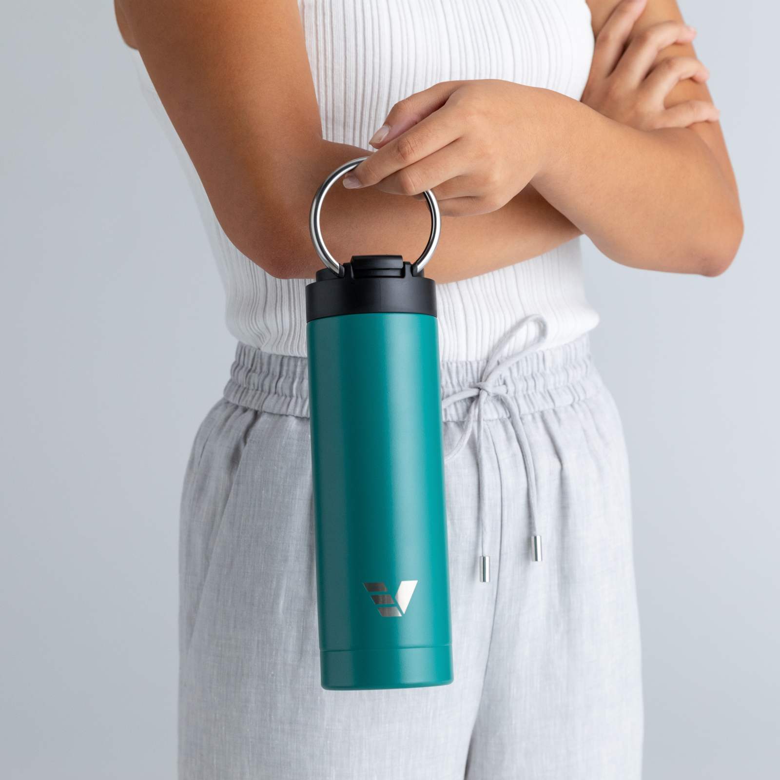 A female holding her Ever Vessel Maxi Teal green stainless steel water bottle by the integrated carry handle.