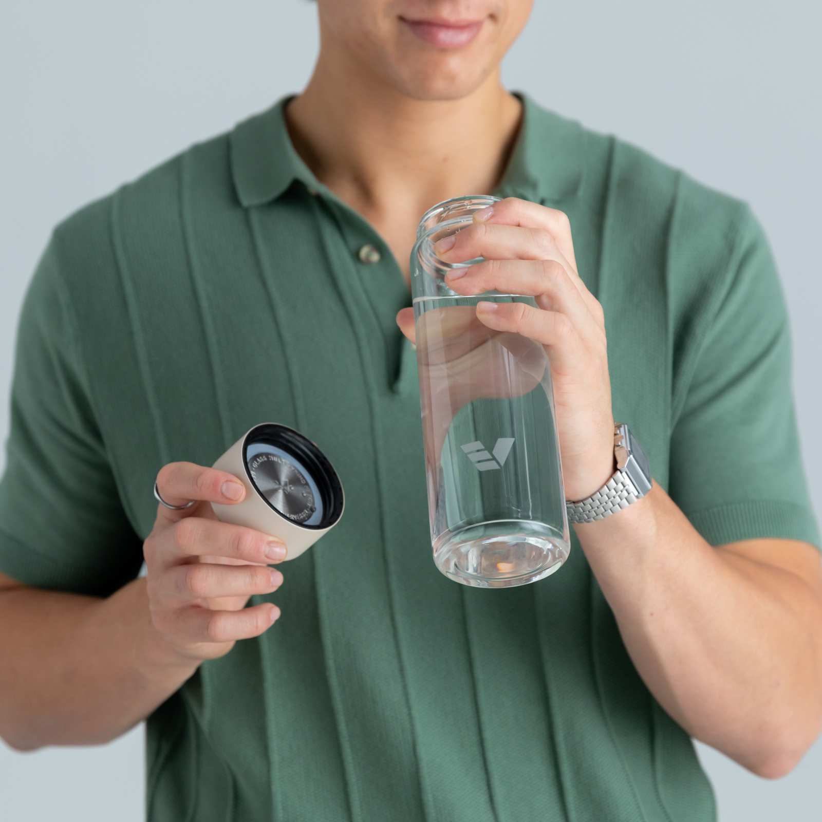 A male about to drink from his Ever Vessel Glass water bottle with a desert beige lid at home.