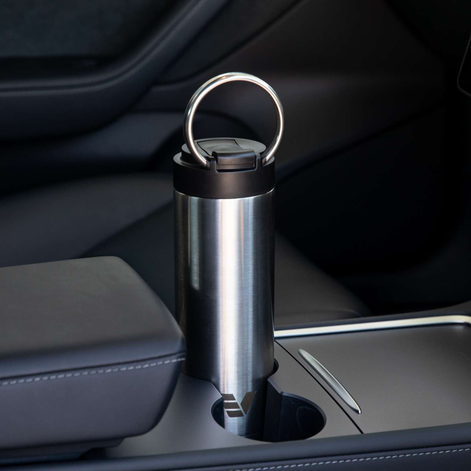 An Ever Vessel Maxi stainless steel water bottle sitting in car cup holder with integrated carry handle deployed.