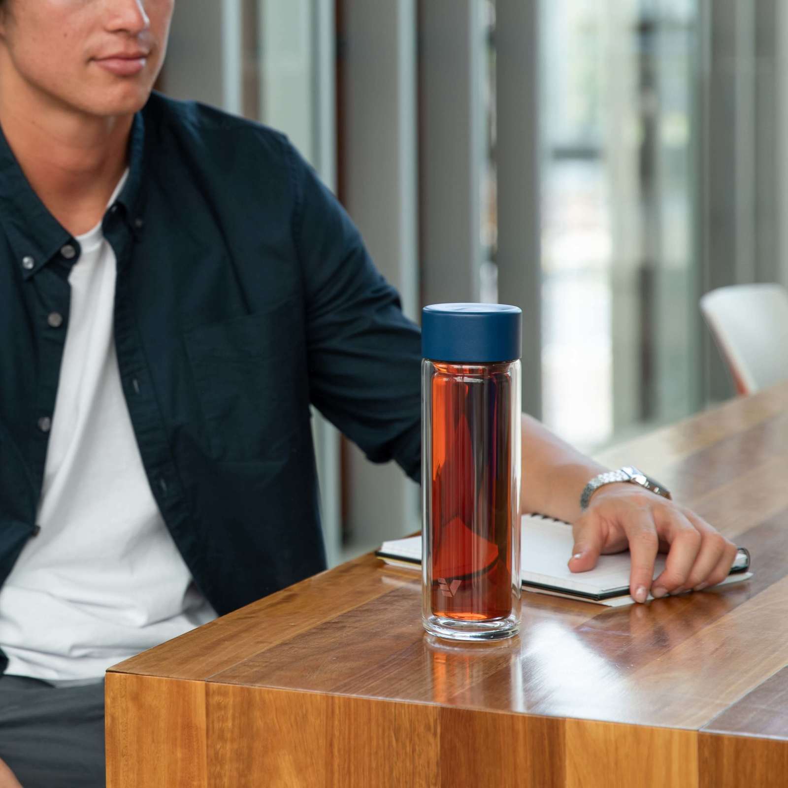 Male using an Ever Vessel Glass Multi Blue double wall glass tea infuser water bottle as a Tea Flask on his desk.
