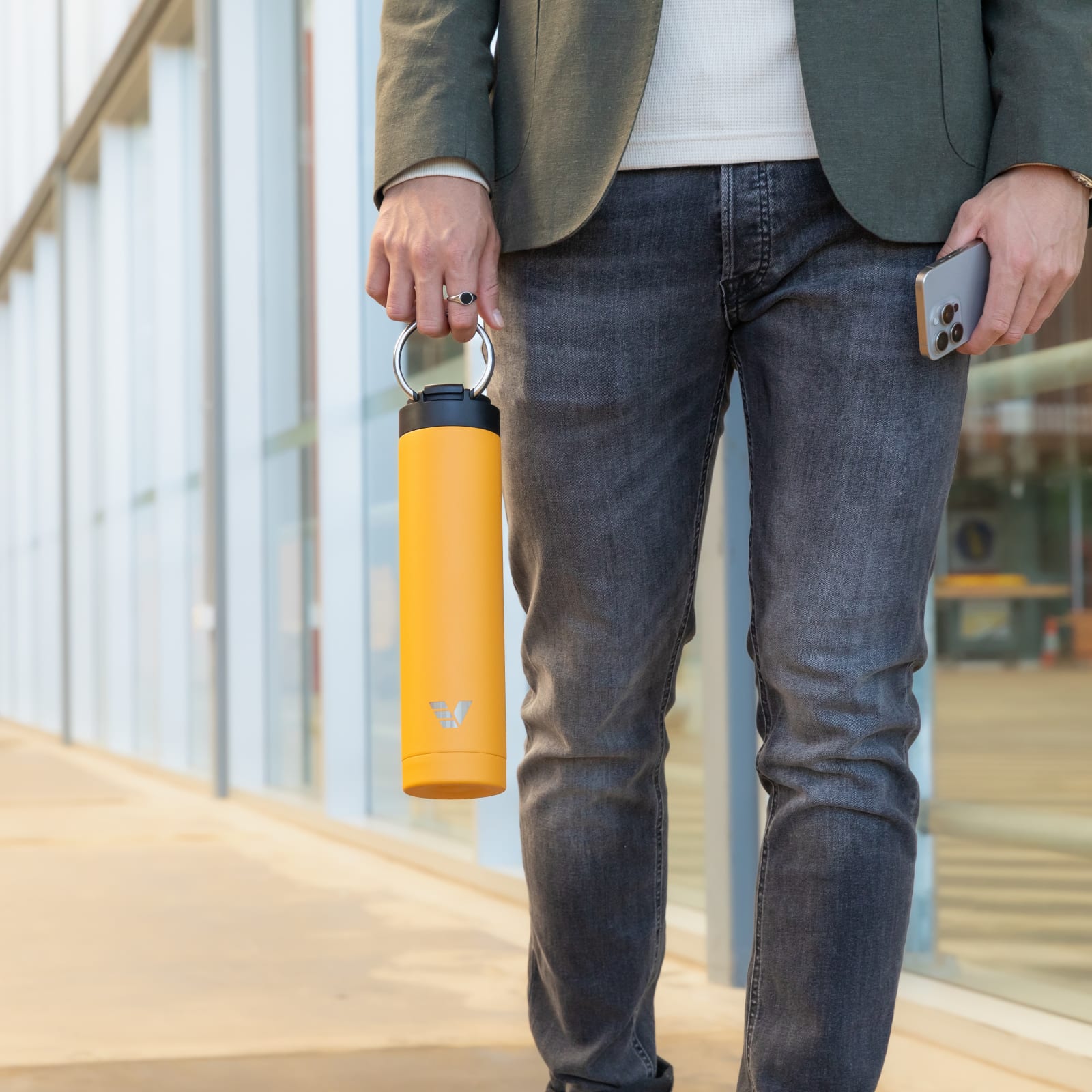 Male carrying his Super Maxi Yellow stainless steel water bottle by the integrated handle on the way to the office.