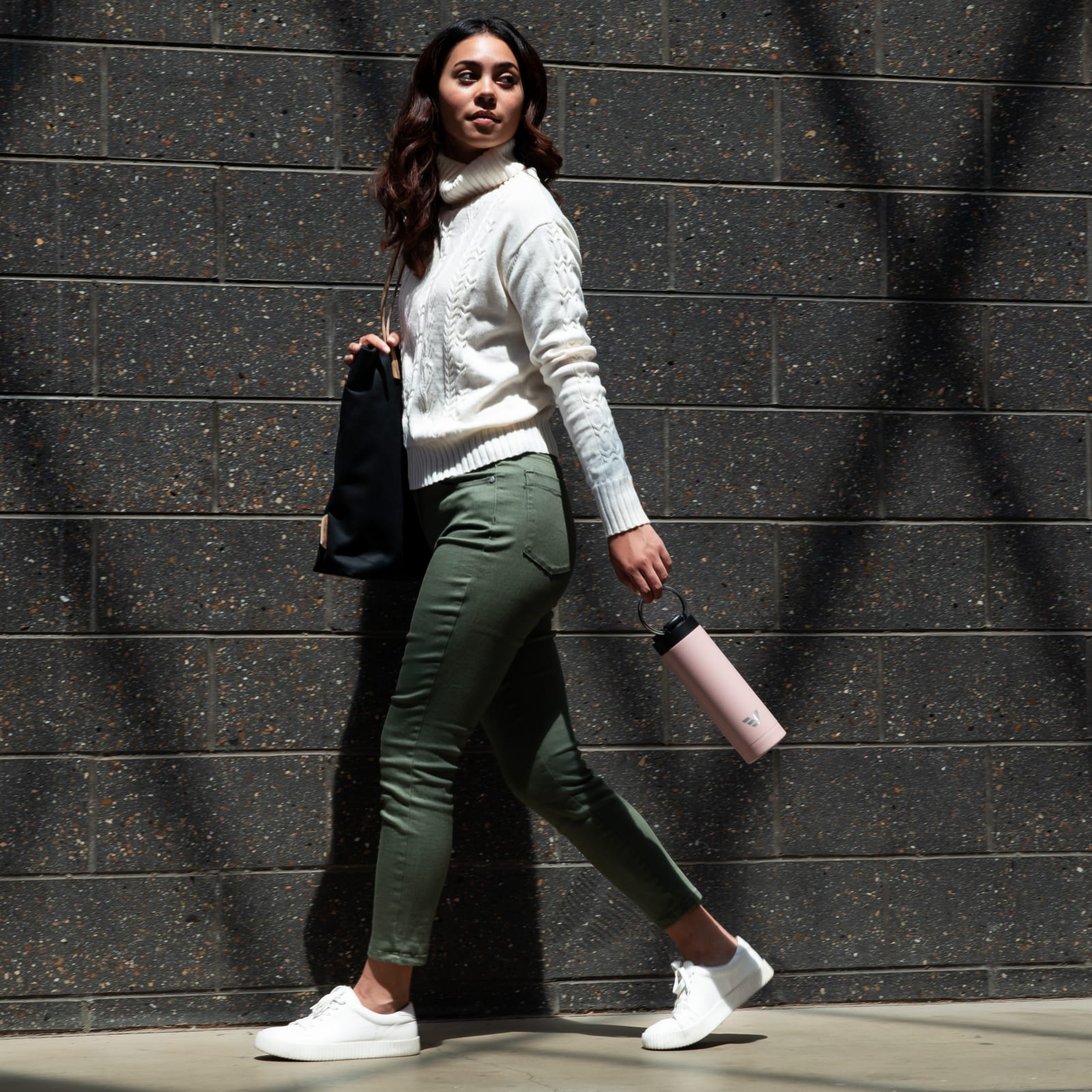 Female carrying her Ever Vessel Maxi Rose pink stainless steel water bottle by the integrated carry handle on the way to work.