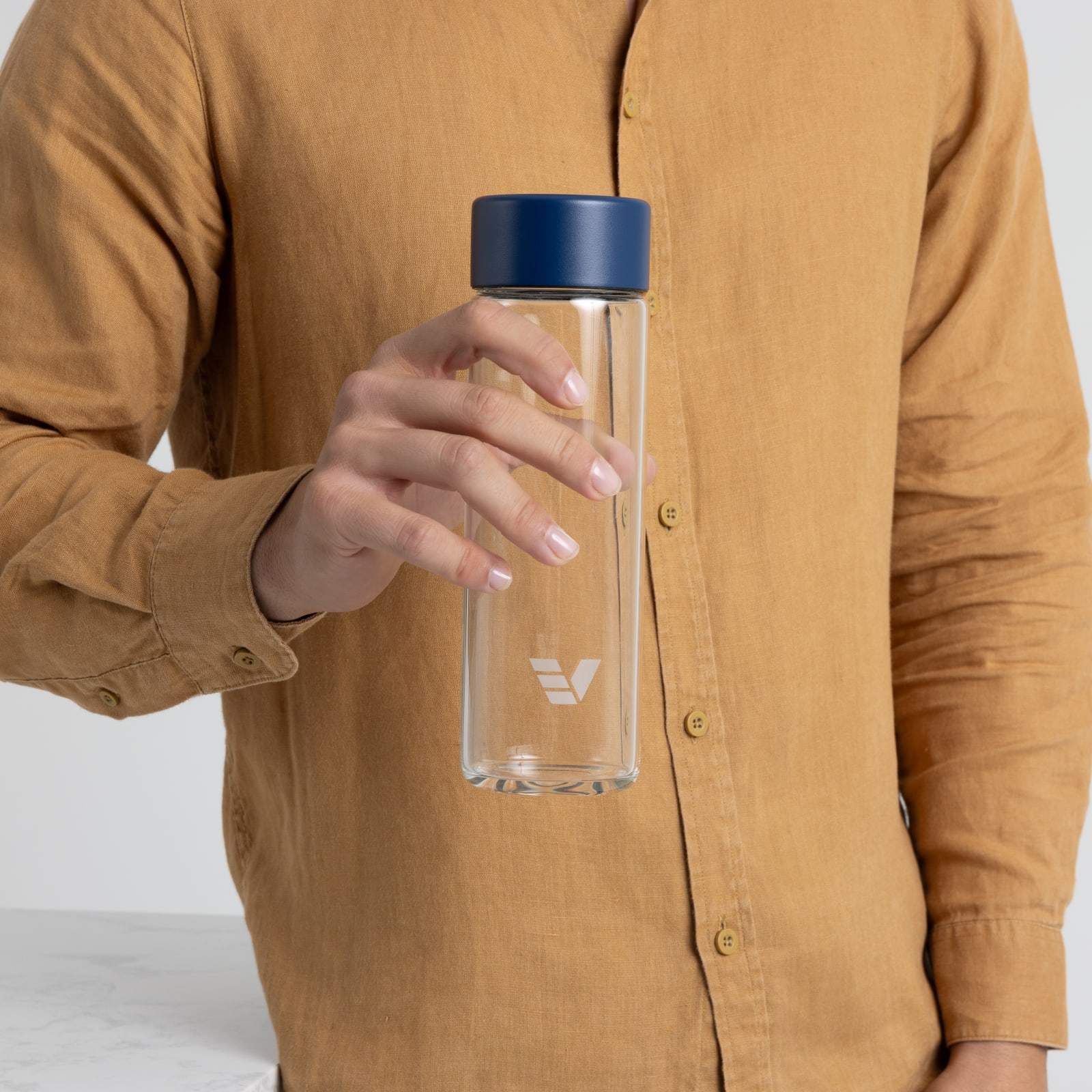 A male holding his Ever Vessel Glass water bottle with blue lid next to the kitchen.