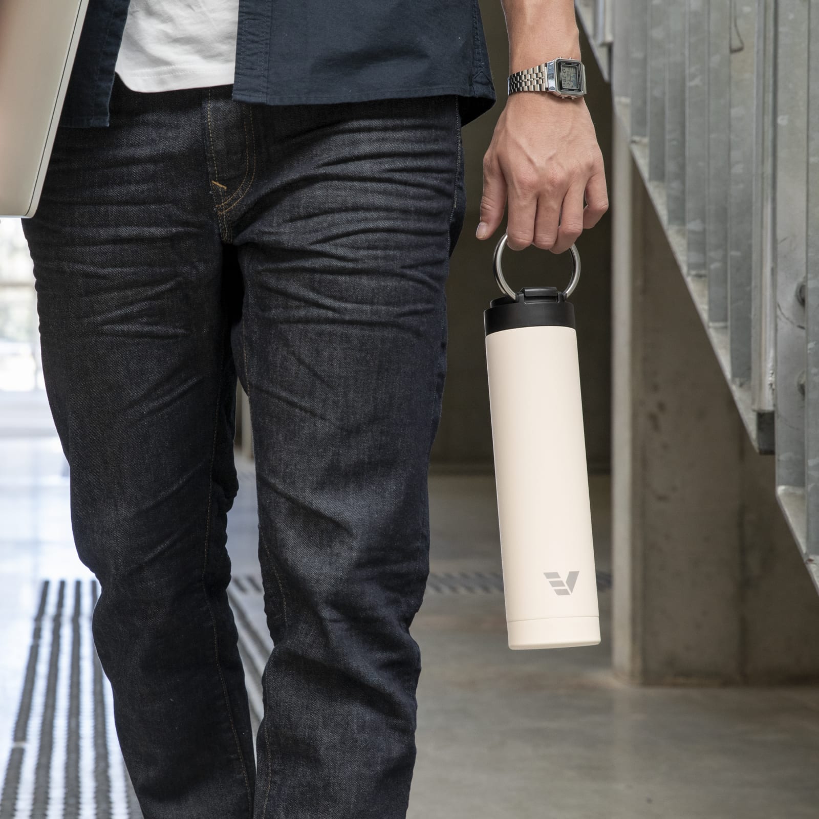 Male carrying his Super Maxi Luna White stainless steel water bottle by the integrated handle on the way to study.