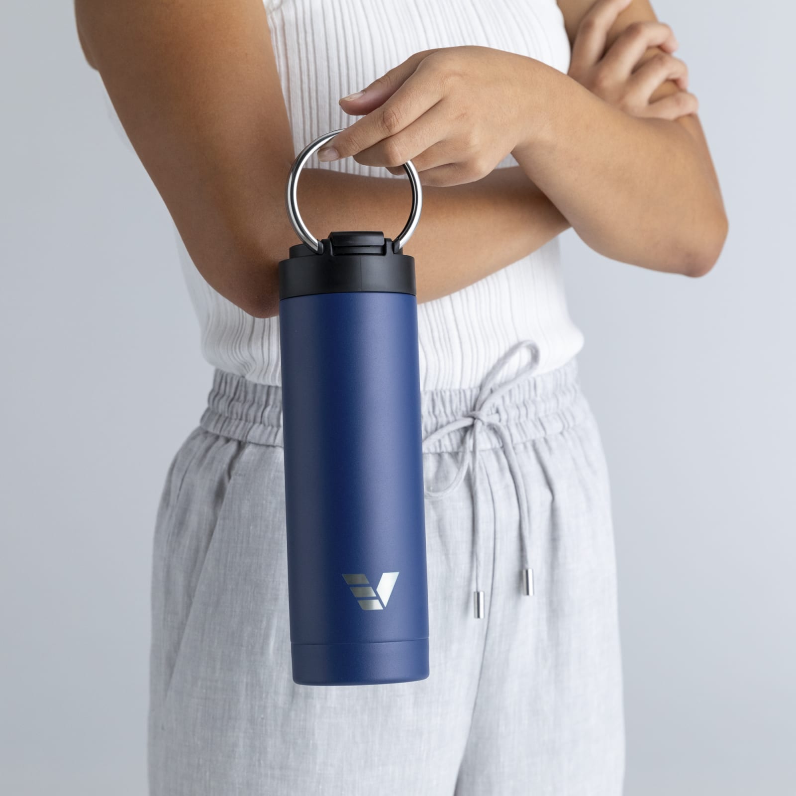 Female carrying her Ever Vessel Maxi Blue stainless steel water bottle by the integrated carry handle at home.
