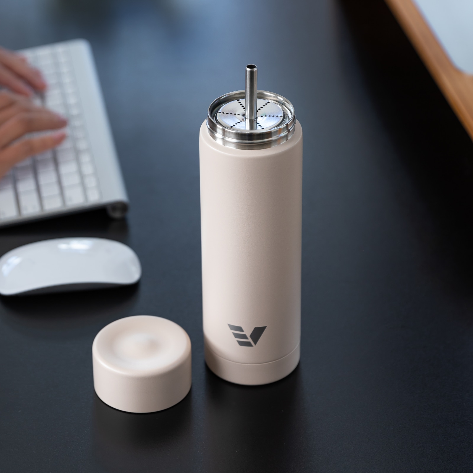 An Ever Vessel Multi Desert beige stainless steel tea infuser water bottle with the Straw Attachment accessory sitting on a desk.